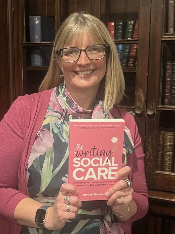 Bryony holding a copy of Rewriting Social Care